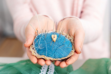 Closeup of person holding pincushion, full of needles