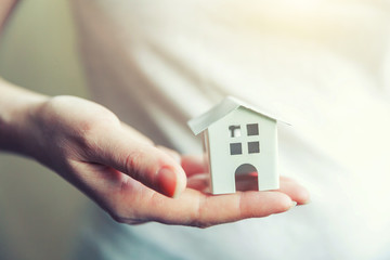 Female woman hands holding small miniature white toy house. Mortgage property insurance dream moving home and real estate concept