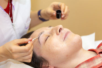 Beautician paint the eyebrows of a young woman