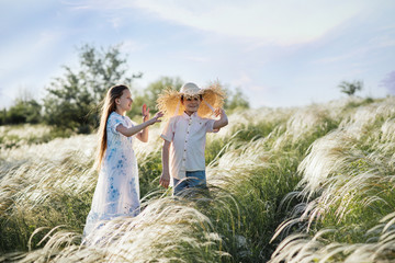 A boy and a girl are playing in the fields. Children in a straw hat. Journey of two children