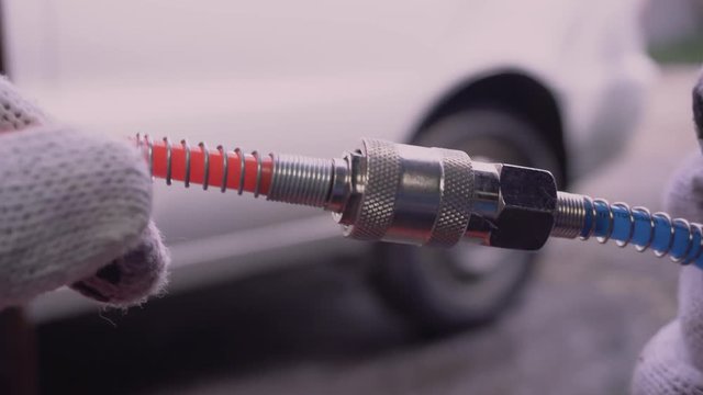 Closeup dolly shot of a man&rsquo;s hand screwing the connection of a tyre / tire inflator to a valve, and switching on the pump.