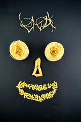 various types of pasta on a dark background. Italian cuisine concept, food face. Flat lay. Top view, copy space
