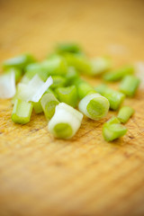 Cut green onion on the brown wooden board background