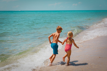 Naklejka premium little girl and boy run play with waves on beach