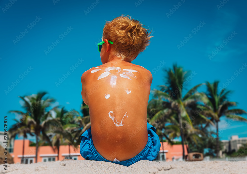 Wall mural sun protection- little boy with suncream at tropical beach