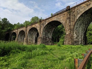 Fototapeta na wymiar Green Pasture with Arched Bridge and Rusted Guard Rail (Viaduct)