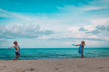 Fototapeta na wymiar kids- boy and girl- play tennis on beach