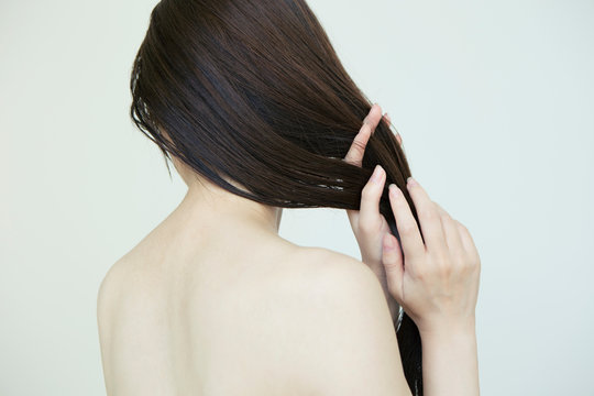 自分の髪の毛を触る女性の後ろ姿