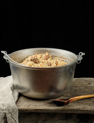 Pilaf is an oriental dish of boiled rice with fat and slices of meat and spices. the dish is cooked in a large aluminum cauldron