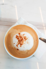 a cup of hot cappuccino on white marble table; shoot by mobile camera.
