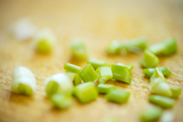 Cut green onion on the brown wooden board background
