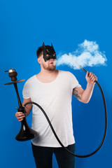 man exhales white thick vapor. hookah flask. the guy is holding a hookah pipe. hookah smoke