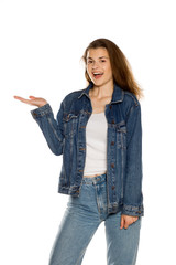 Young beautiful woman in jeans holding imaginary object on her hand on white background