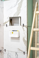 Bathroom renovation concept. Marble ceramic tiles with spacers and grey cement walls in bathroom, renovating and working in toilet, space for text. Repairing