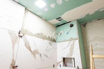 Bathroom renovation concept. Marble ceramic tiles with spacers and grey cement walls in bathroom,...