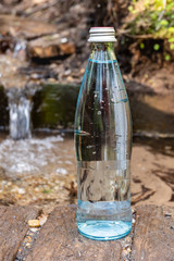 Natural ecological spring water. Glass bottle with cold spring water stands in nature.