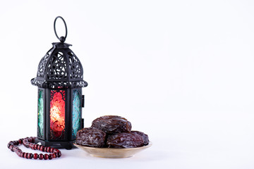 Ramadan food and drinks concept. Ramadan Lantern with arabian lamp, wood rosary, dates fruit and lighting on white background.