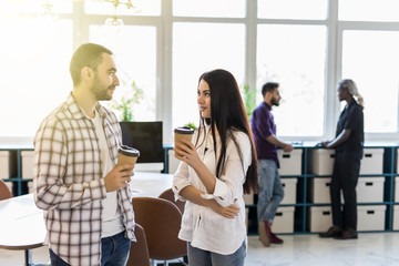 Casual coworkers drinking coffee in front of the office