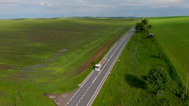white trucks and cars ride along the road near large beautiful fields with green wheat aerial background nature wallpapper