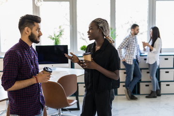 Businessman pouring coffee for collegues in a meeting room. Businessmen and businesswomen take coffee break after conference. Happy formal business team drinking coffee and relaxing at work.