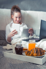 Young woman eating healthy breakfast in bed Soft cozy photo of a young teen girl on a bed with a...