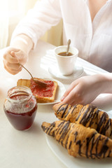 healthy woman eating corn flakes cereal while sitting and having breakfast at the kitchen table