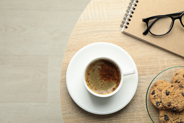 Cup of coffee, cookies, notebook and glasses on wooden table, top view and space for text. Break time