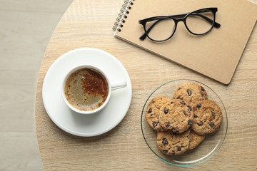 Cup of coffee, cookies, notebook and glasses on wooden table, top view and space for text. Break time