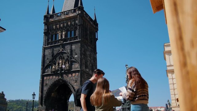 A young friends travelers walking on a background of Bridge Tower of Charles Bridge. Holding a map and finding a way to go