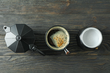 Cup of coffee and coffee maker on wooden table, space for text and top view