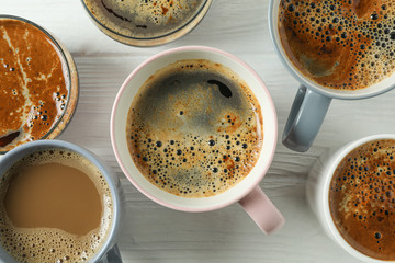 Cups of coffee on white wooden background, closeup and top view