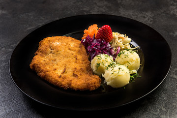 Pork meat served with potato and salad on plate