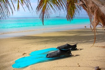 Blue flippers  lie on the shore of a tropical island with white sand in blue lagoon, Indian Ocean, Maldives