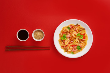 Glass noodle with shrimps and vegetables on the red background