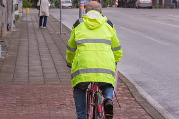 an adult cyclist rides a bicycle on the sidewalk. cyclist in a reflective team in street...