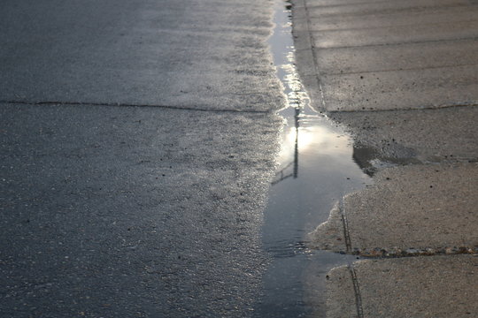 Reflection of sky in water puddle on pavement 