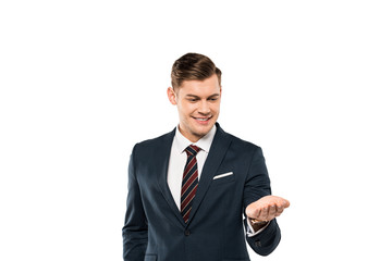 cheerful businessman in suit looking at hand isolated on white