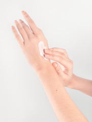Spa treatment. Close Up of female hands applying hand cream. Woman holding cream tube and applying moisturizer cream on her beautiful hands for clean and soft skin.