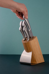 Woman Hands Pulling Out Stainless Steel Chef's Knives From A Bamboo Stand