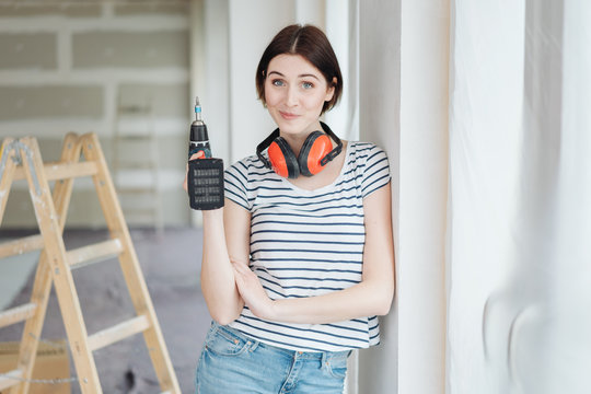 Wry young woman holding a power drill
