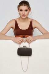 Cropped shot of lady with smokey eyes, wearing bronze velvet crop top and leather belt with lacing,...