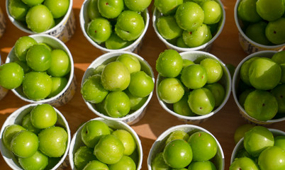 Top view of green plums or greengage in paper cup on sale in the street in Turkey, popular spring fruits with a very sharp sour taste in Iran