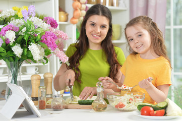 Cute little girl with her mother cooking together