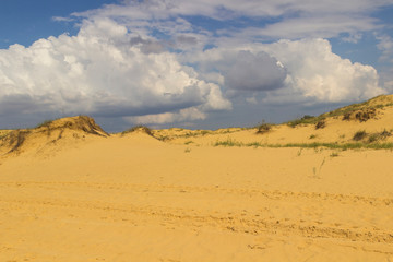 Fototapeta na wymiar Sand dunes in the blue sky clouds, the track of a motor-car on the sand.