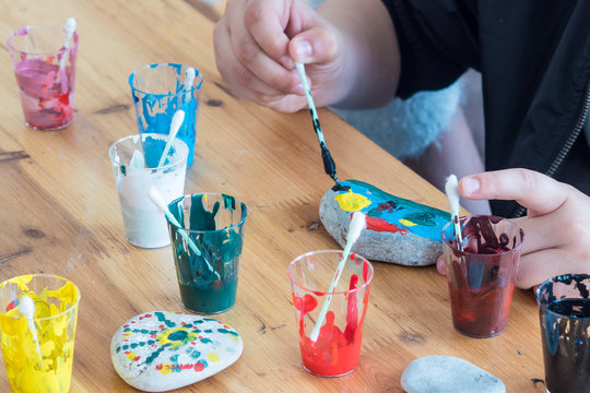 Children's entertainment -paint stones. Painted with  paints stones and jars of paint, leisure for the child, children's creativity. Coloring sea stones