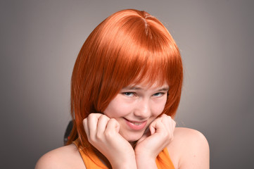 Portrait of cute girl with red hair posing in studio