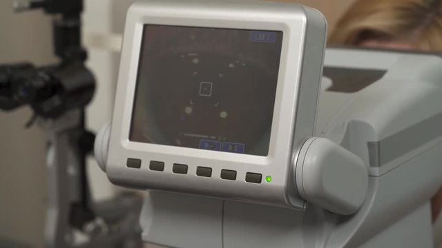 An ophthalmologist performing eyesight check-up using professional modern automated refractor. Cornea of the eye on the screen.