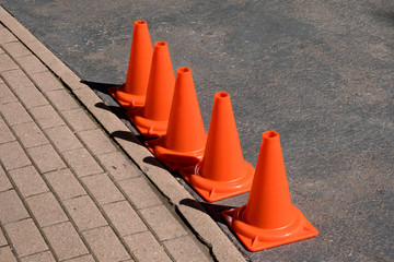A line of five traffic cones separates the pavement and the road
