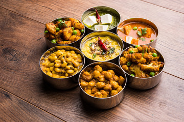assorted Indian/Pakistani food in stainless steel bowls creating pattern or design, selective focus