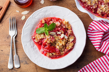 Crumble with berries in a white plate. Top view. Wooden background.